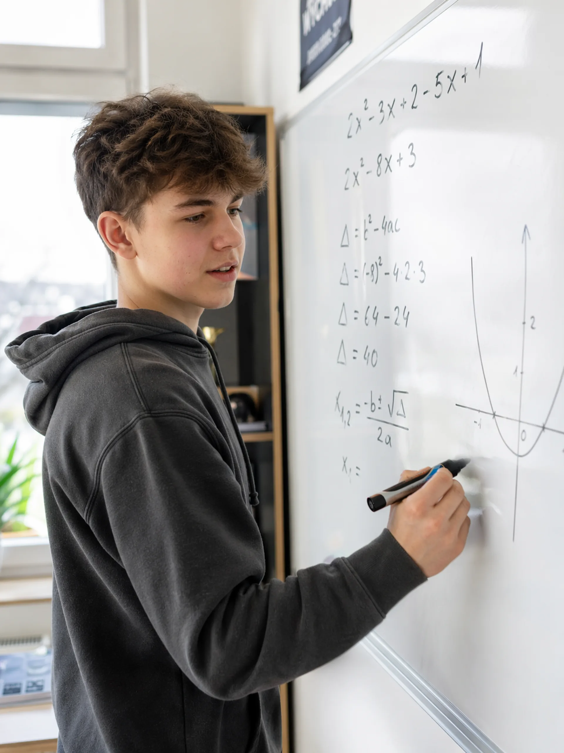 Nastolatek rozwiązuje równanie kwadratowe na tablicy — moment zrozumienia